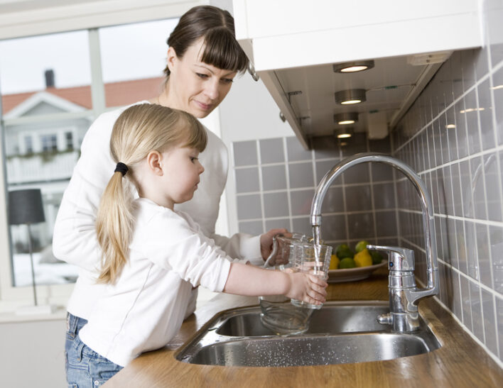 Mutter und Tochter füllen einen Wasserkrug am Waschbecken