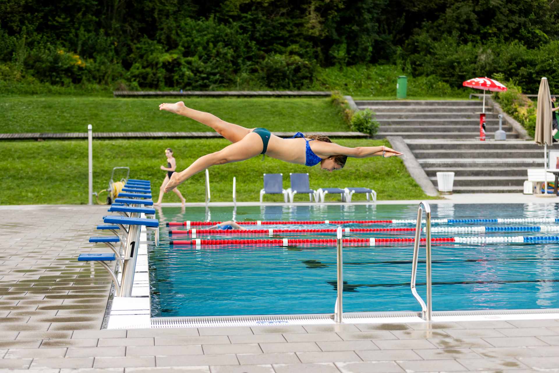 Ein junges Mädchen macht einen Kopfsprung in das große Schwimmbecken