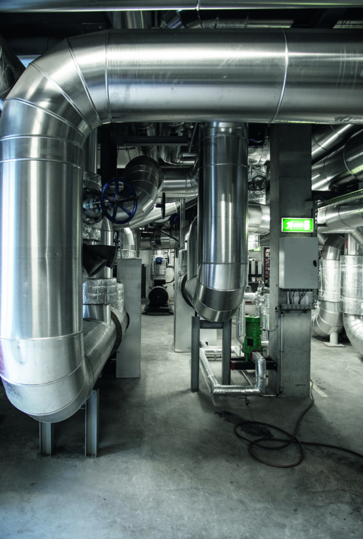 Industrieller Raum mit großen, silbernen Rohrleitungen und Ventilen in einer technischen Anlage