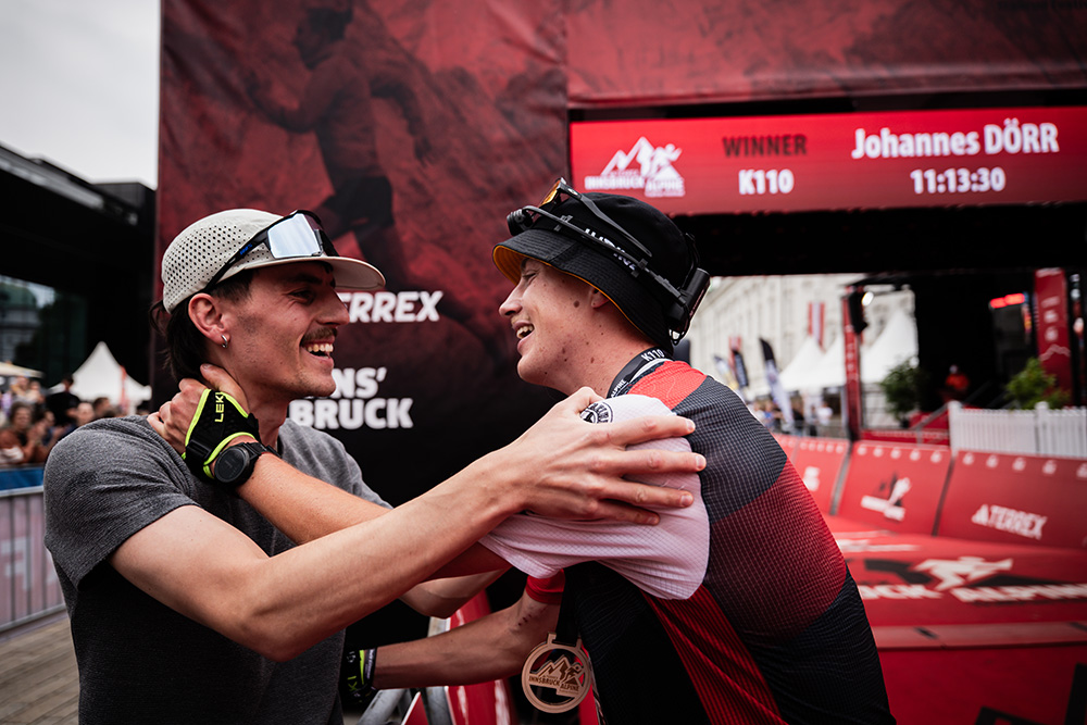 Der glückliche Sieger des K110, Johannes Dörr, bei dem Zieleinlauf der K110-Distanz des Innsbruck Alpine Trailrun Festivals 2025 in herzlicher Umarmung.