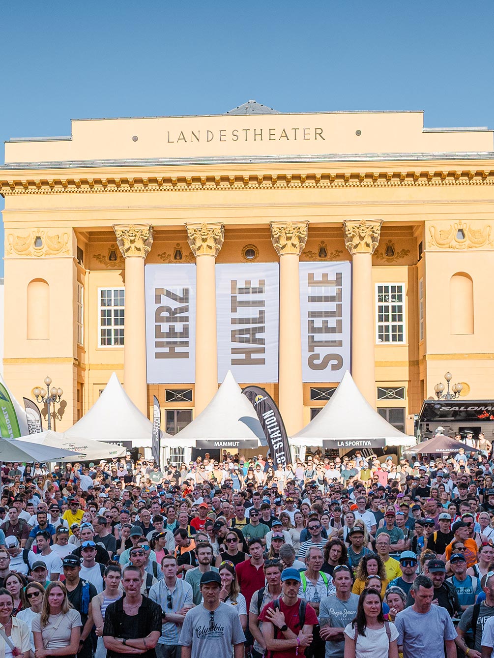 Große Menschenmenge vor dem Tiroler Landestheater in Innsbruck mit Trailrunning-Expoständen während des IATF.