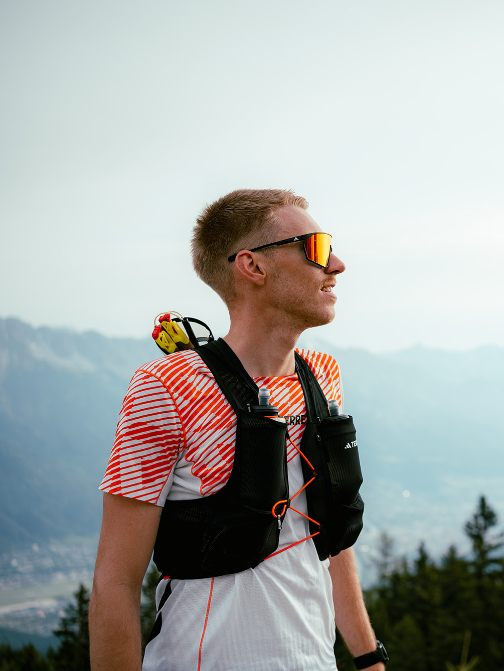Ein Trailrunner im Profil mit Sonnenbrille, Laufweste und Adidas Terrex Shirt vor der Bergkulisse von Innsbruck beim IATF.