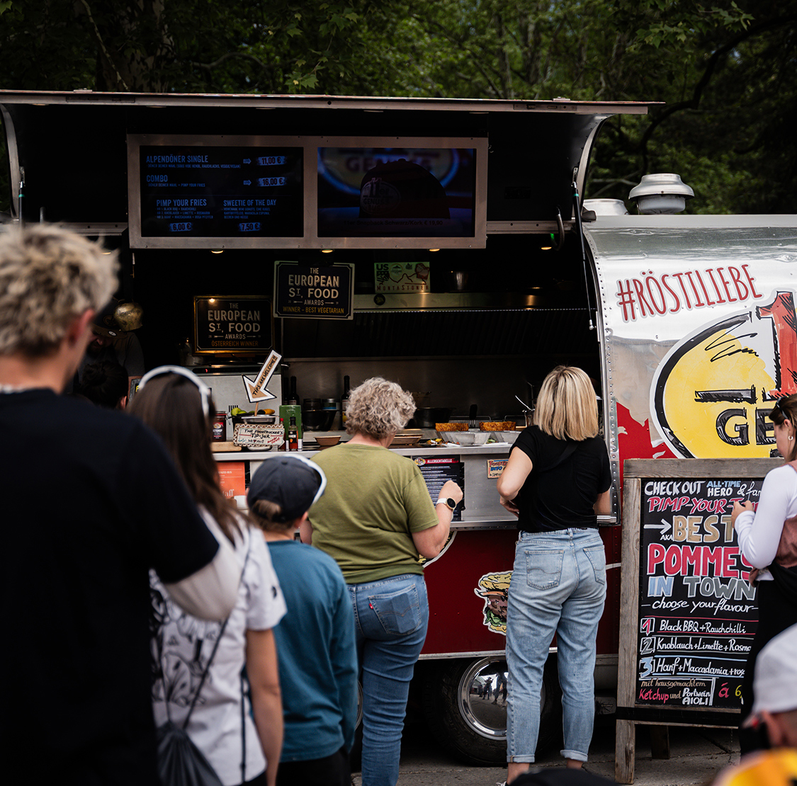 Besucher stehen Schlange an einem Foodtruck auf dem Eventgelände des Innsbruck Alpine Trailrun Festivals.