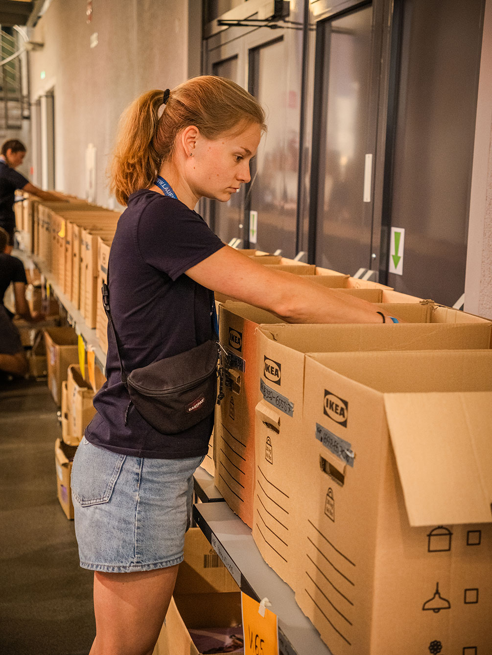 Eine konzentrierte Volunteer-Mitarbeiterin sortiert beim IATF in Innsbruck Starterkuverts in nummerierte Kartons für die Startnummernausgabe.