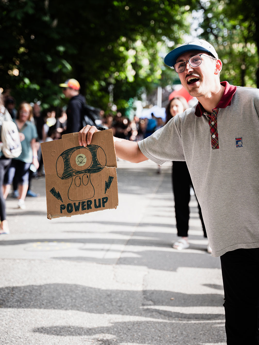 Ein begeisterter Zuschauer hält ein handgemaltes "Power Up"-Schild mit einem Pilz-Motiv in die Höhe, um die Läufer beim Innsbruck Alpine Trailrun Festival anzufeuern.