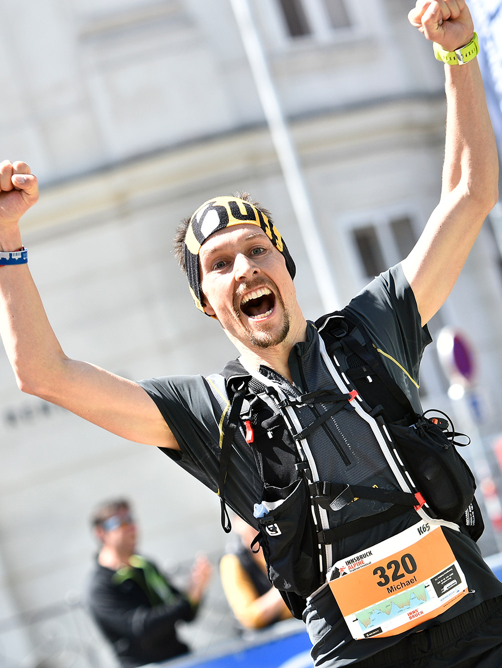 Ein euphorischer Trailrunner der K65 Distanz des Innsbruck Alpine Trailrun Festivals reißt im Ziel beide Arme hoch und schreit seine Freude heraus.