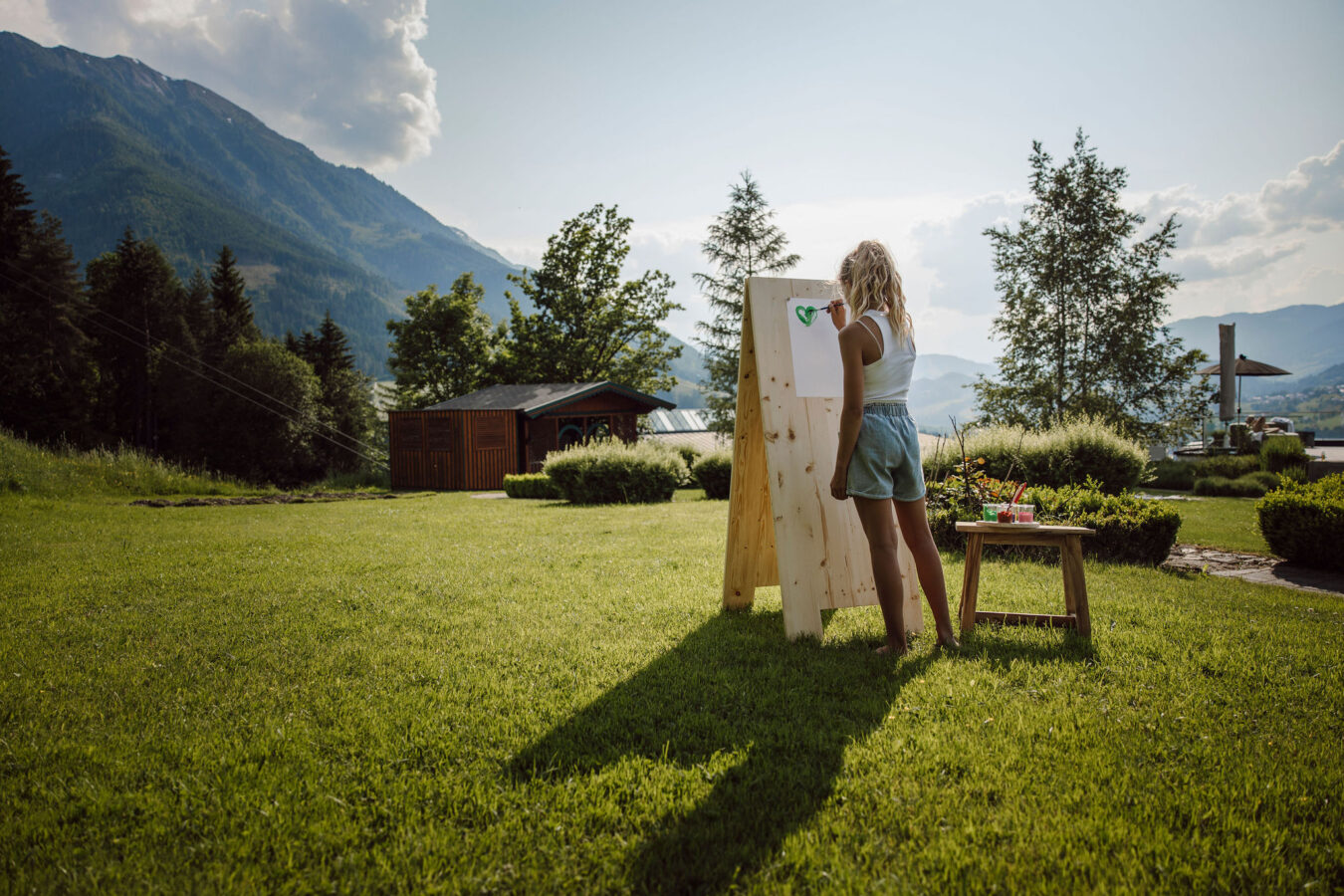 Mädchen beim Malen im Garten im Alpina Alpendorf