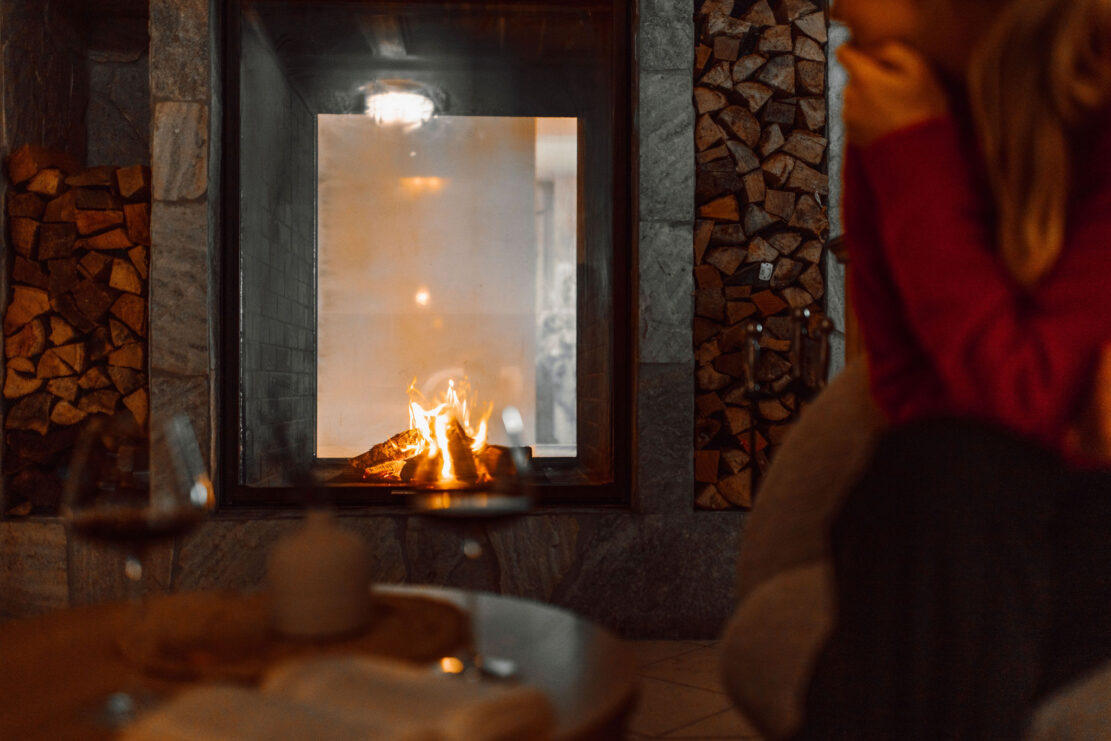 In der Lobby vom Alpina Alpendorf brennt Feuer am offenen Kamin.