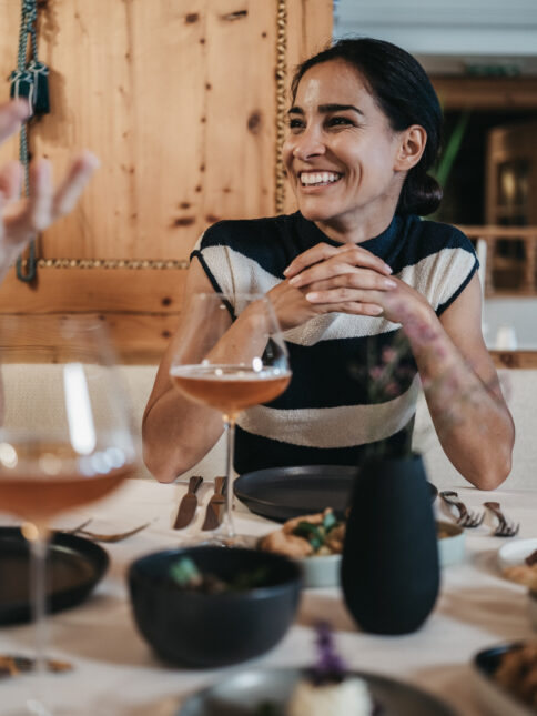 Eine Frau genießt das Dinner am Abend im Alpina Alpendorf