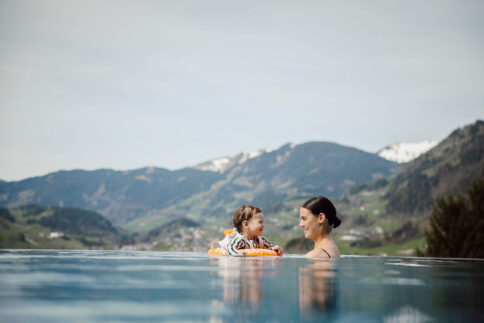 Mutter und Kind im Rooftoppool im Alpina Alpendorf mit Weitblick über die Berge