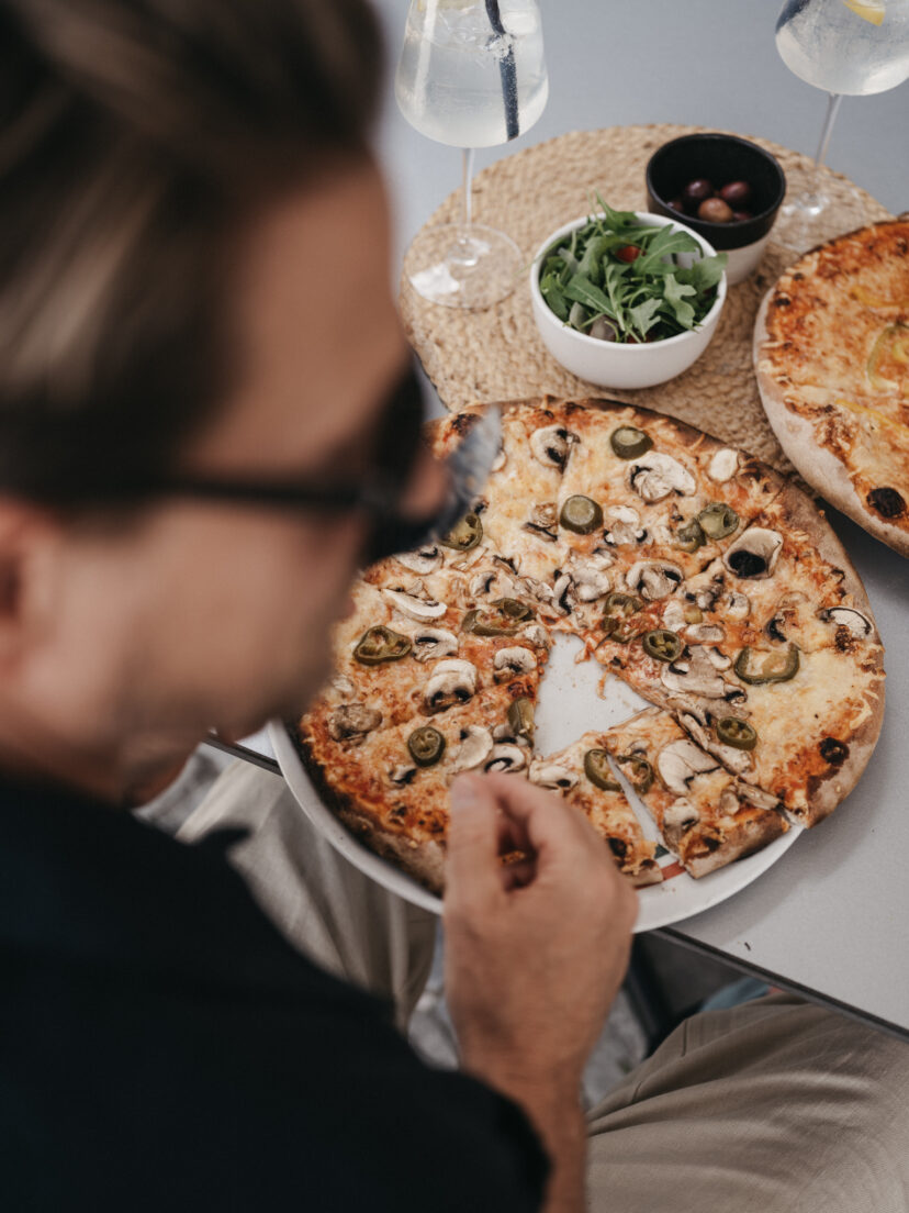 Ein Paar genießt die Holzofen Pizza auf der Terrasse beim BistrO Alpendorf