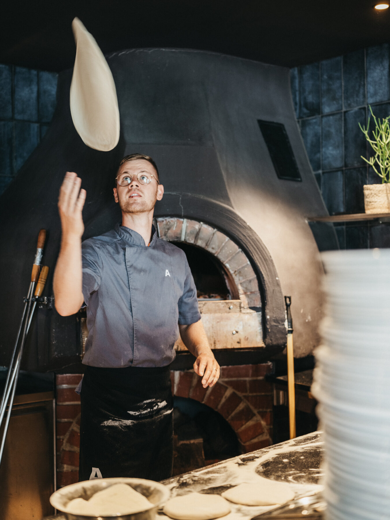 Pizzakoch beim backen einer Holzofen Pizza im BistrO Alpendorf
