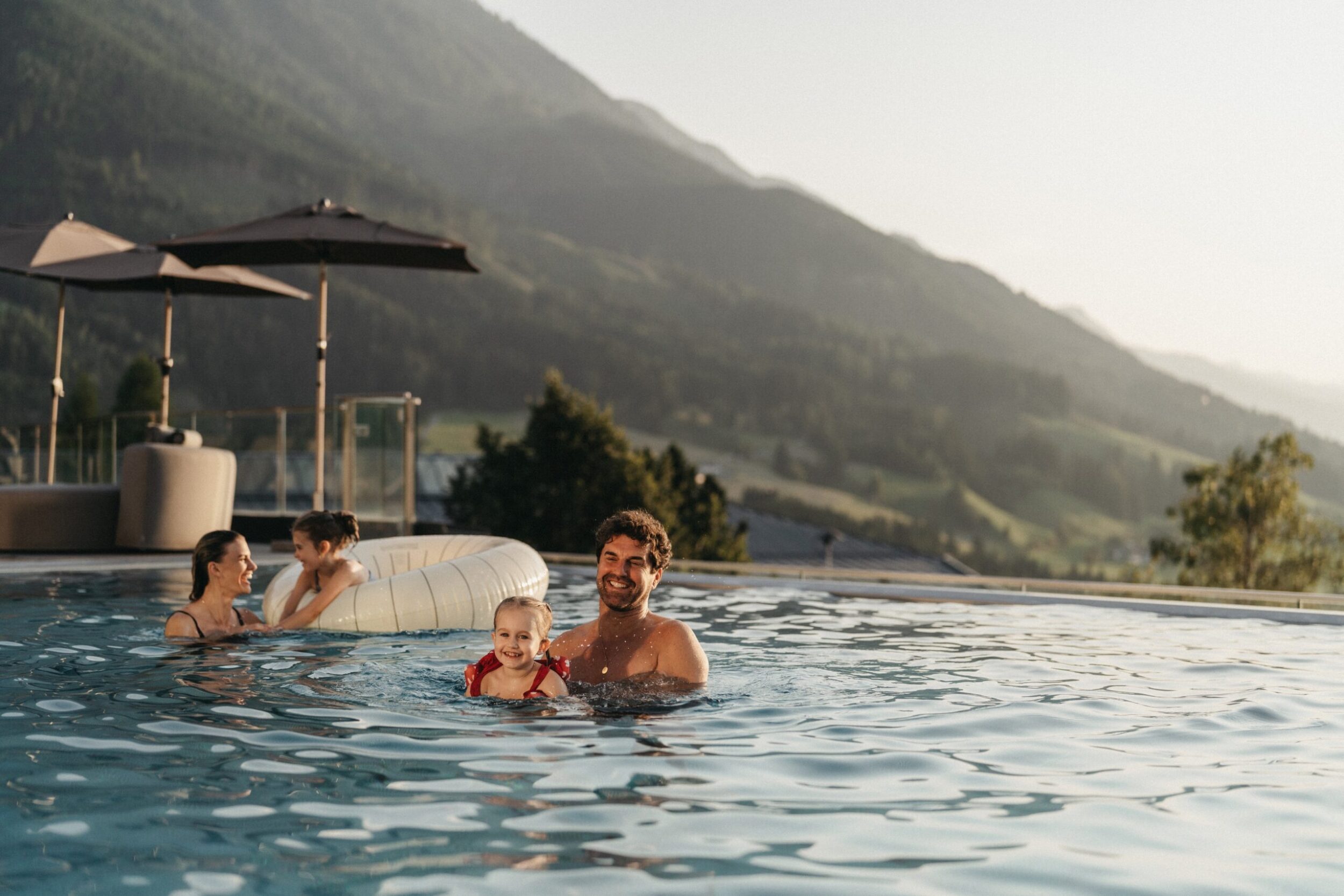 Familie genießt die Aussicht auf die Bergwelt im Rooftop-Pool im Alpina Alpendorf