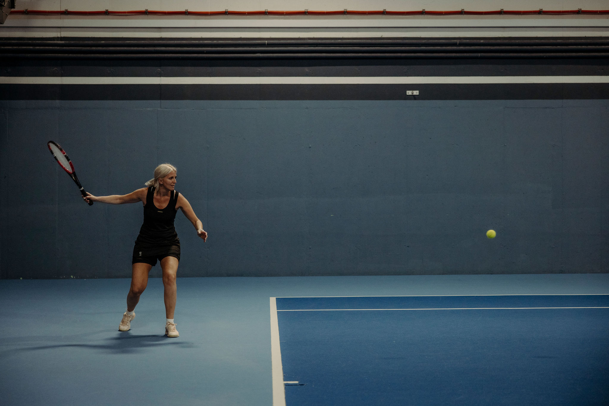 Eine Frau beim Tennistraining im Tennishotel Alpina Alpendorf.