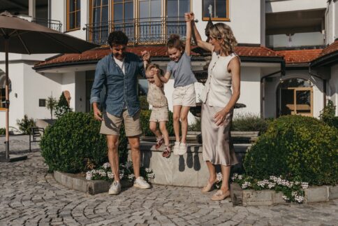 Eine Familie genießt den Familienurlaub bei Sonnenschein und Weitblick über die Berge im Alpina Alpendorf