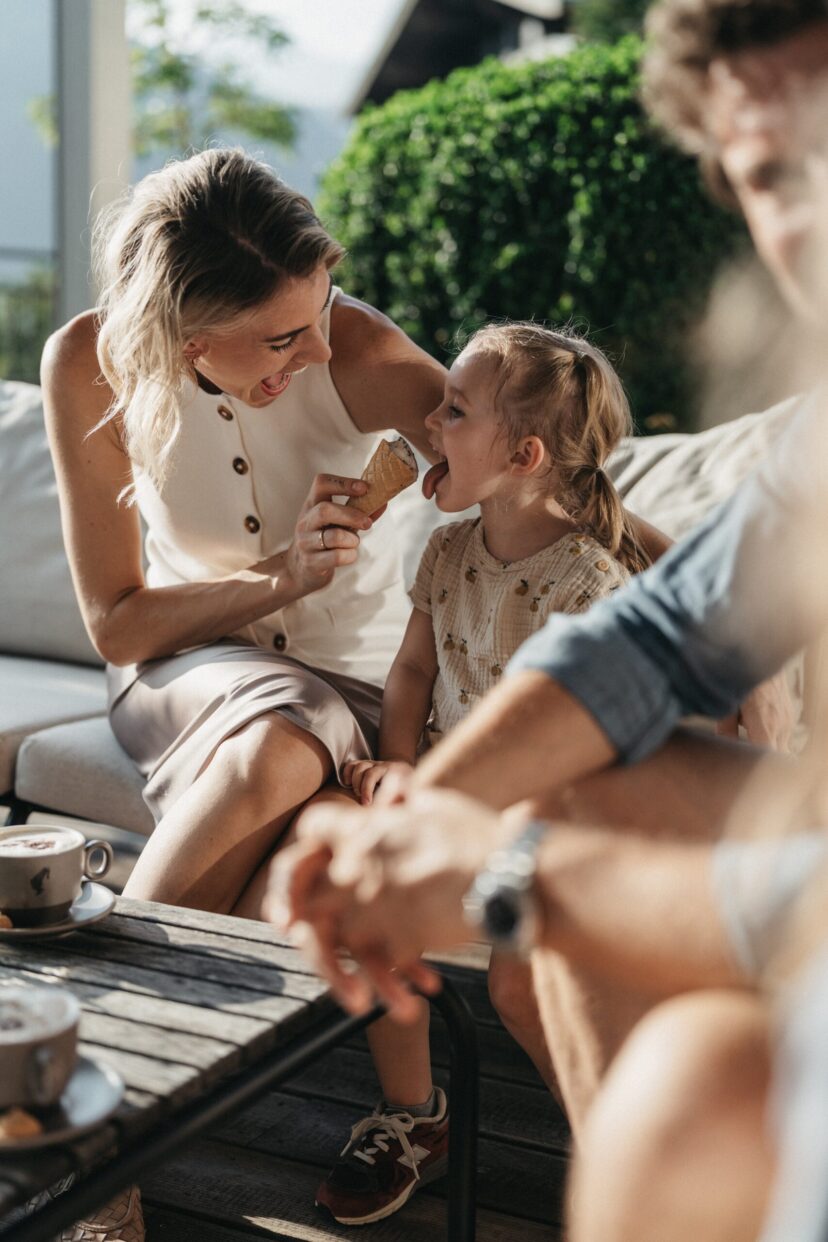 Eine Familie isst ein hausgemachtes Eis auf der Terrasse vom Familienhotel Alpina im Sommer.