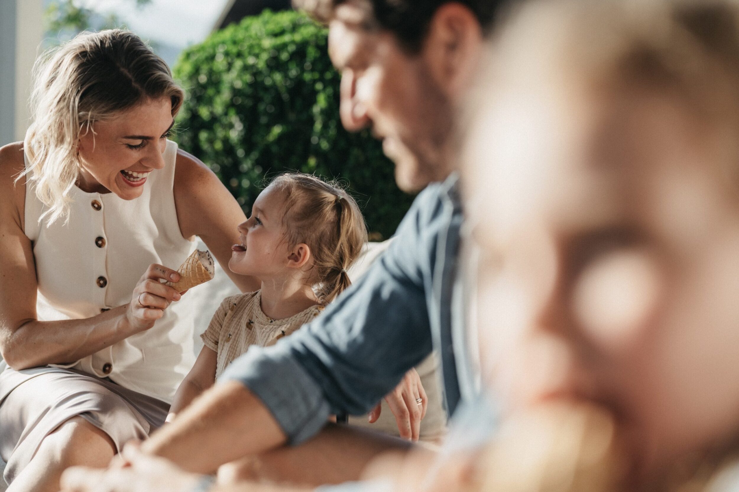 Eine Familie isst ein hausgemachtes Eis auf der Terrasse vom Familienhotel Alpina im Sommer.