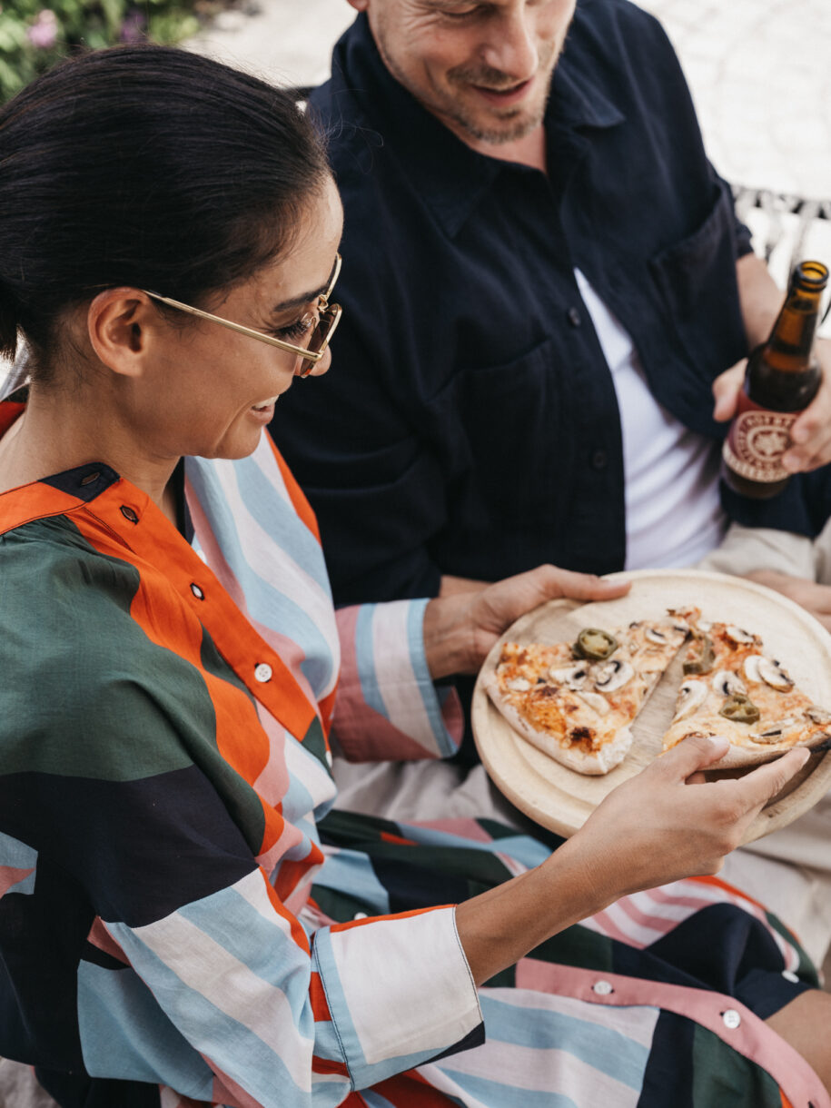 Ein Paar genießt die Holzofen Pizza auf der Terrasse beim BistrO Alpendorf